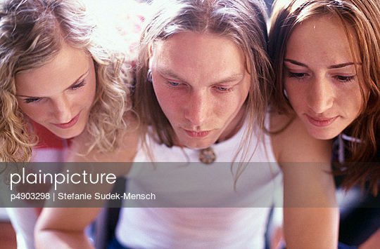 Three young People looking closely at something