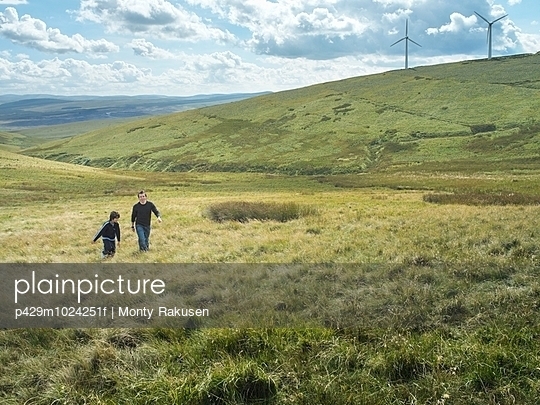 Brothers walk up hill together at windfarm