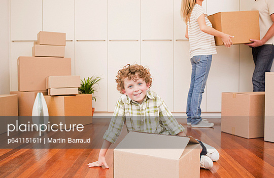 Boy sitting with box on the floor of his new house