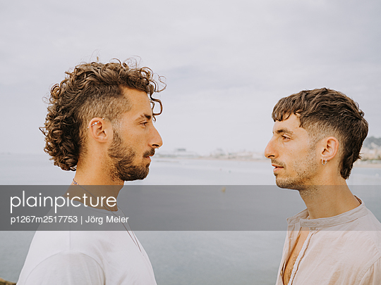 Two young men look at each other, Barcelona skyline in the background - p1267m2517753 by Jörg Meier