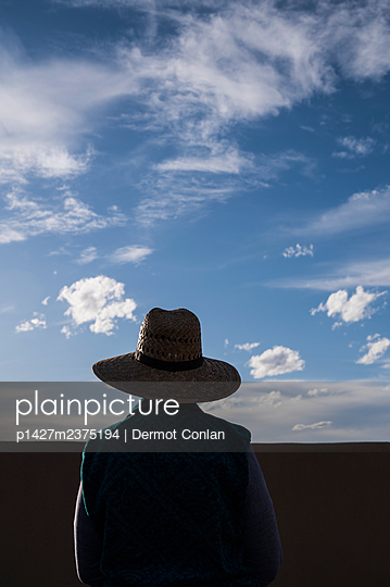 Rear view of woman in straw hat standing in desert landscape - p1427m2375194 by Dermot Conlan