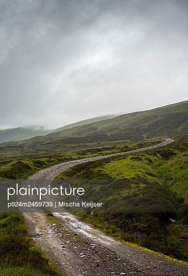 UK, Scotland, Storm clouds above green hills and dirt road - p924m2459739 by Mischa Keijser