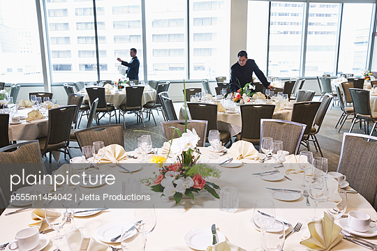 Waiters setting tables in dining room