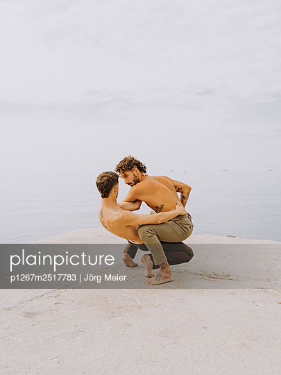 Expressive dance, two young men in a dancing pose by the sea - p1267m2517783 by Jörg Meier