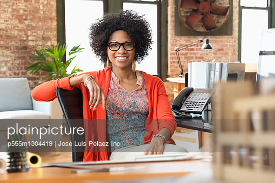 Smiling Black businesswoman sitting at desk - Stock Image - Everypixel